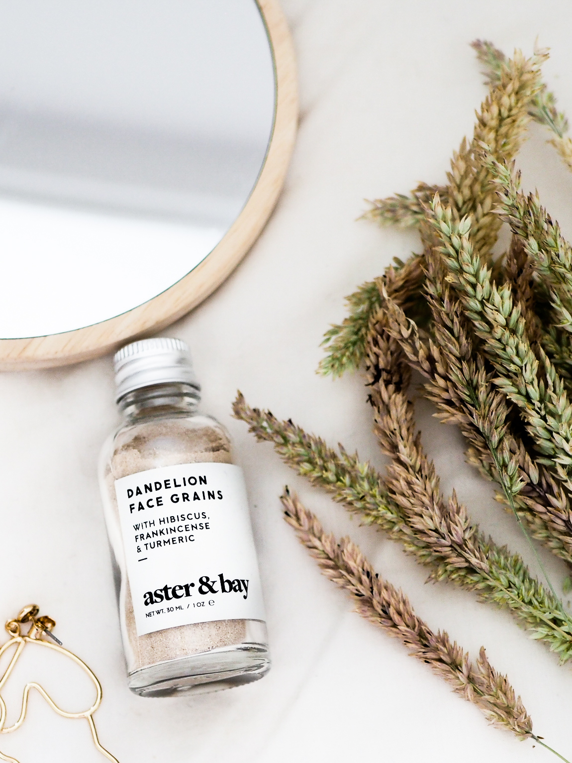 flatlay photo of aster and bay dandelion face grains with grass decoration