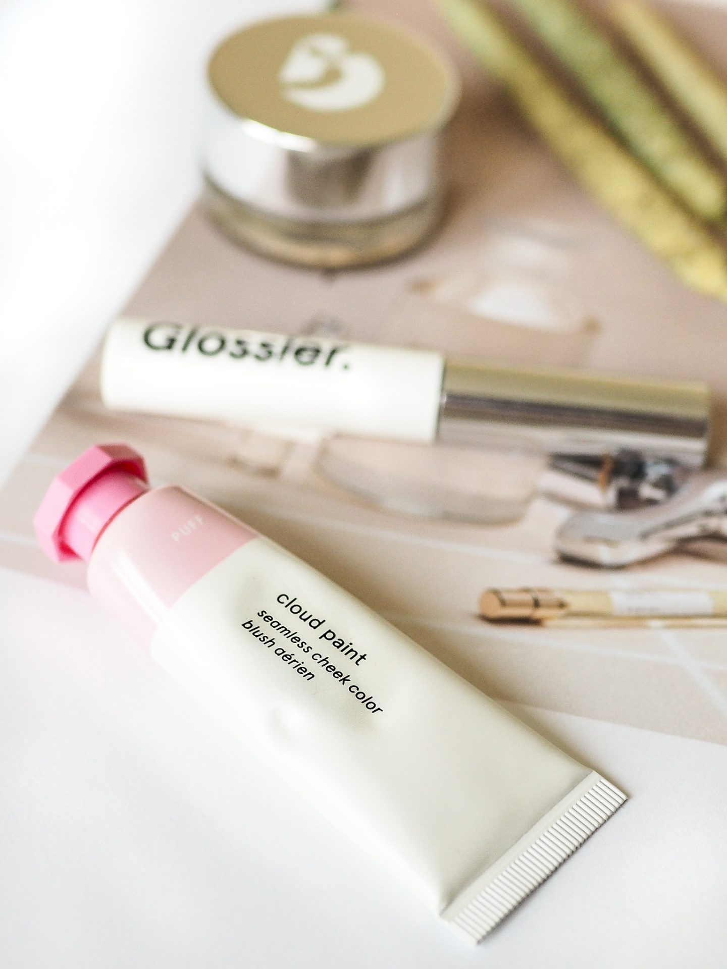 close up shot of Glossier cloud paint with other Glossier products in the background
