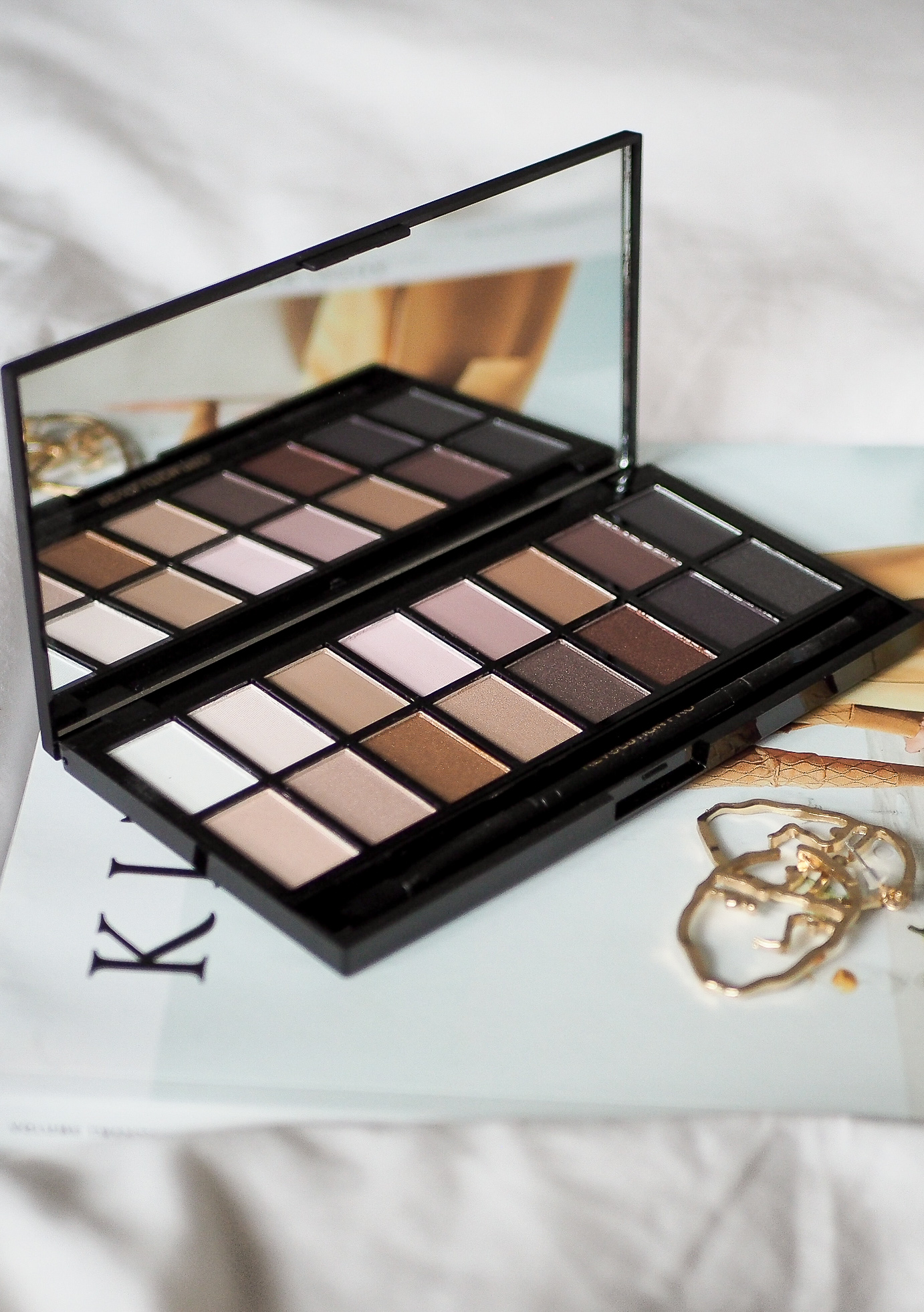 makeup revolution eyeshadow palette sitting on Kinfolk magazine with face earrings