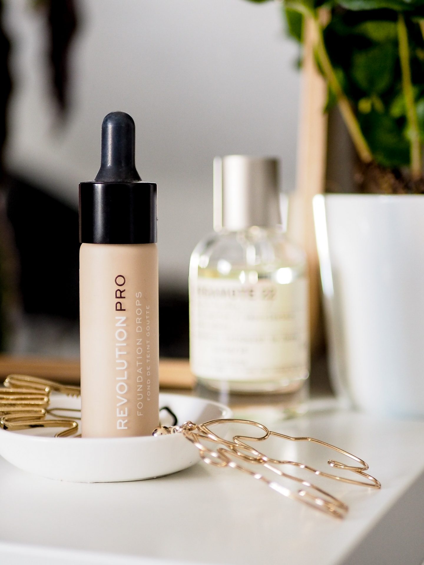 revolution pro drops foundation sitting on dressing table with mirror and perfume with plant