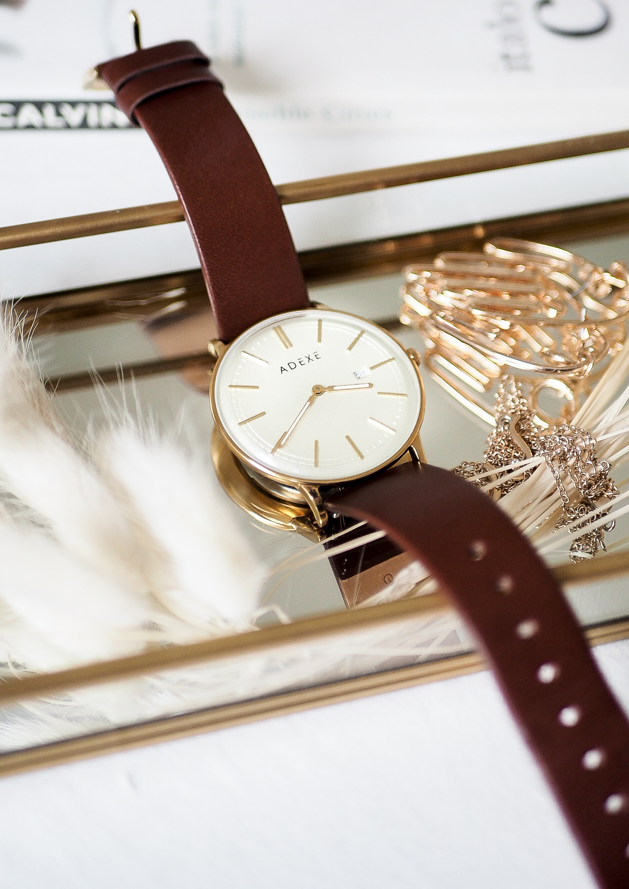 adexe meek grande in gold and brown resting on jewellery tray with bunny tail grass and earrings