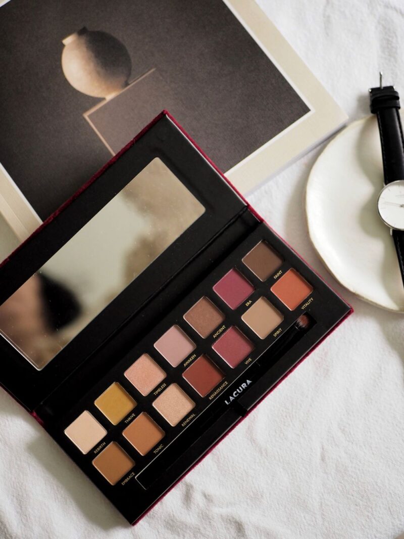 Aldi Lacura Velvet eyeshadow palette in Revival lying flat next to a magazine and watch.
